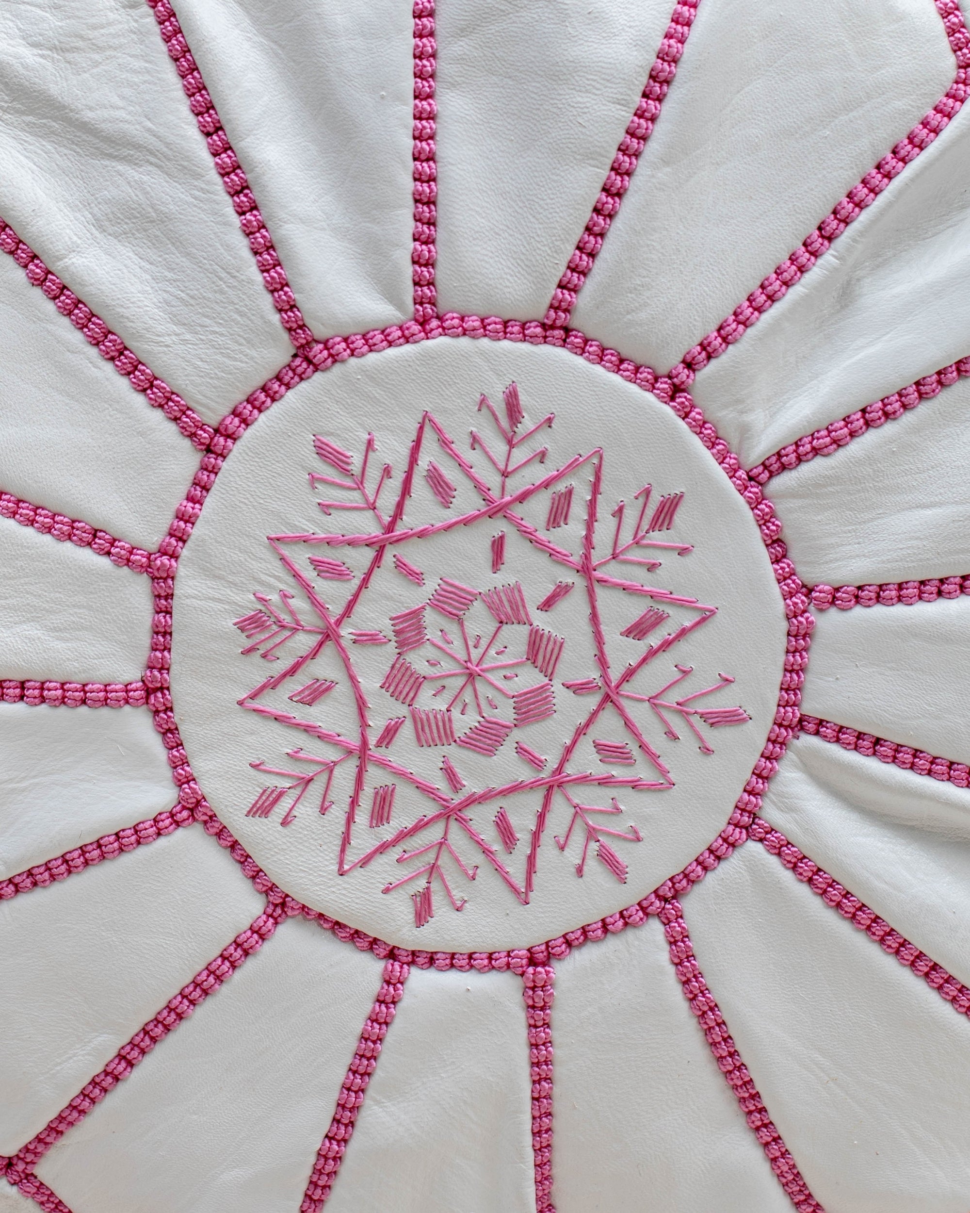 White with pink stitching pouf styled in living room as ottoman