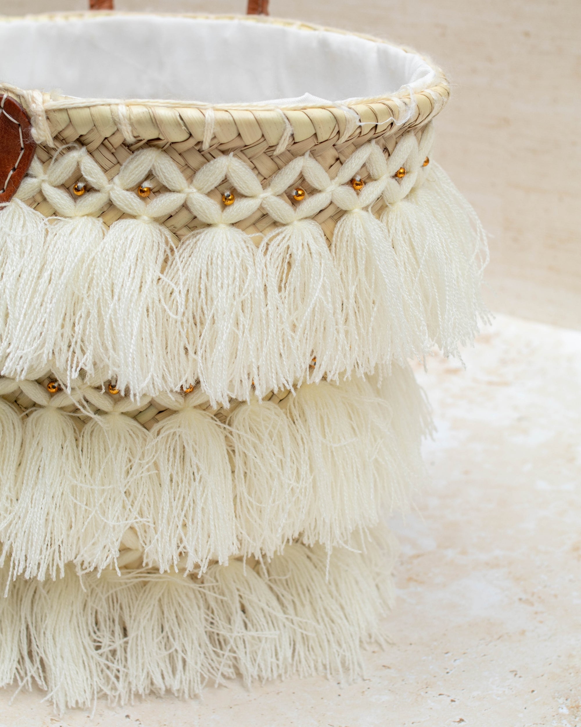 Woven basket with tassels and beads on a light background